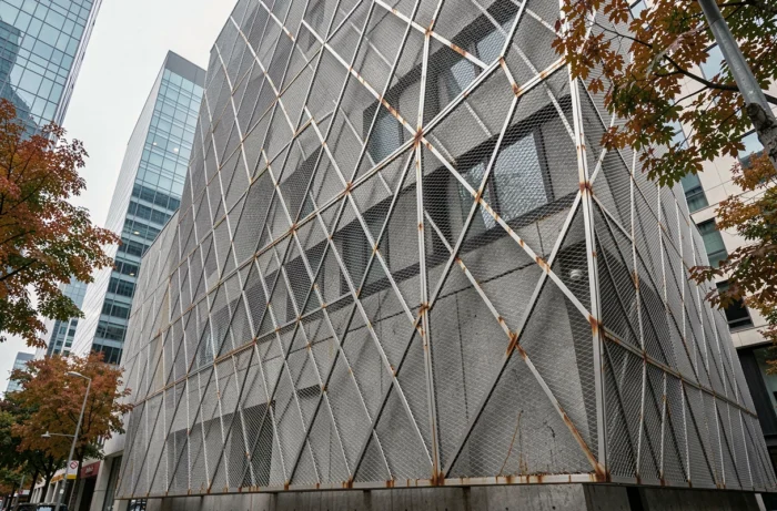 Façade architecturale moderne habillée d'une résille métallique en acier inoxydable à motifs géométriques losange, vue en contre-plongée depuis la rue